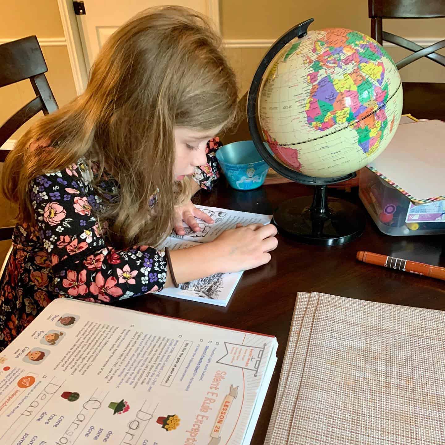 Simply Learning Together Schoolwork Girl studying with globe and educational materials at home.